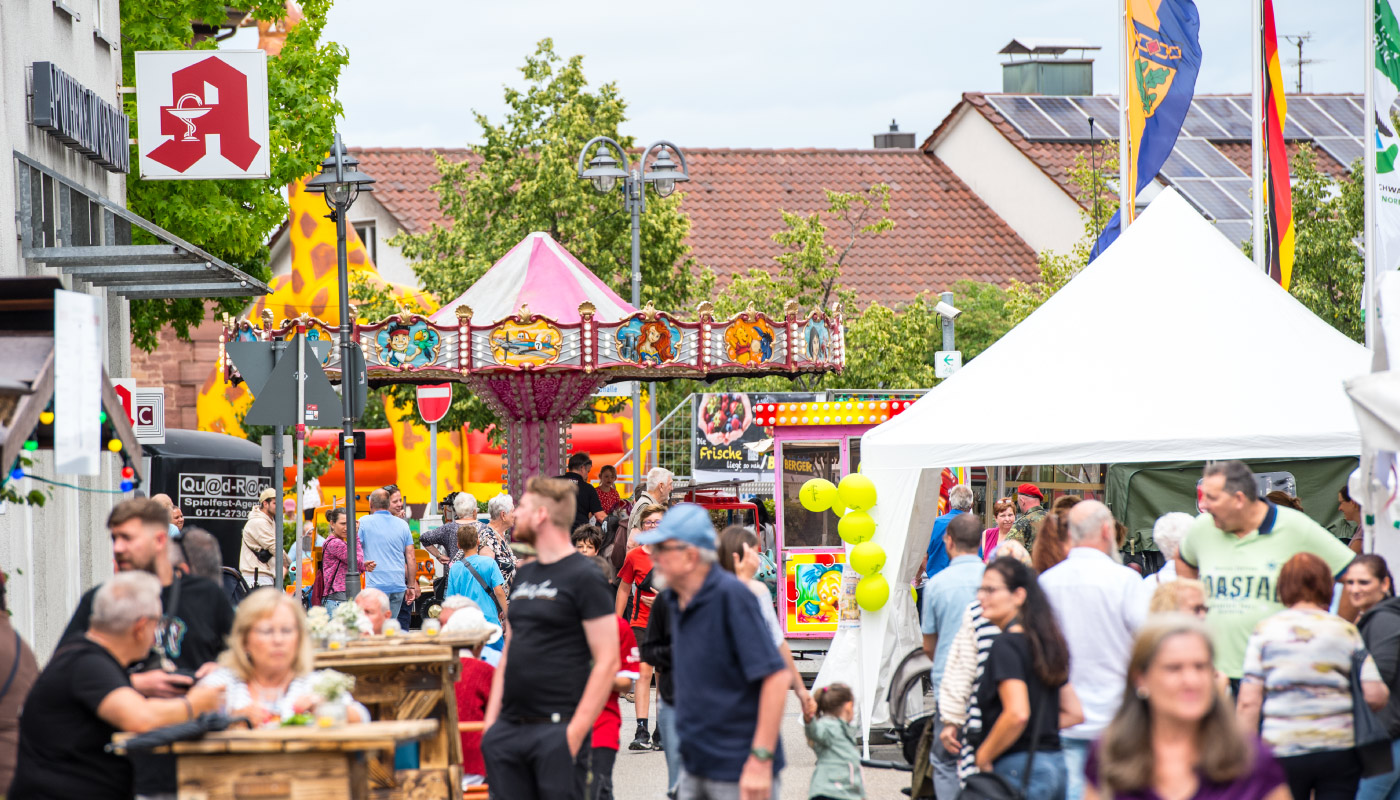 Buntes Straßenfest in Birkenfeld mit Karussell, Essensständen und fröhlicher Menschenmenge.  Wenn du magst,